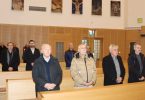 Grupa muškaraca u formalnoj odjeći stoji u crkvi tijekom vjerske ceremonije
