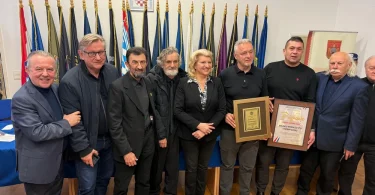 Grupa muškaraca u formalnoj odjeći s plaketom i признањем na ceremoniji