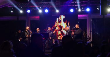 Membres klape Zvizdan pjevaju na blagdanskom koncertu uz plave i ljubičaste svjetlosti