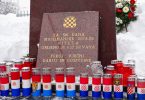 Spomen-ploča od crvenog mramora s hrvatskom šahovnicom i svijećama te crno-bijelim zastavama