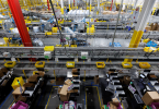 Nadzor nad Amazon skladištem s brojevima žutih robotskih nosača paketa između redova police