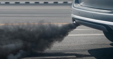 Gust crni dim izlazi iz auspuha automobila na cesti