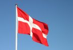 Danska zastava sa bijelim nordijskim križem na crvenoj podlozi koja se vijori na vjetru