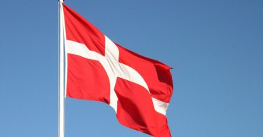 Danska zastava sa bijelim nordijskim križem na crvenoj podlozi koja se vijori na vjetru