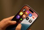 Ruka drži iPhone s ikonama društvenih mreža na zaslonu