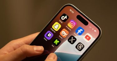 Ruka drži iPhone s ikonama društvenih mreža na zaslonu