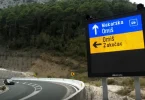 Plavi putokaz s natpisom Makarskog Omišu na horskoj cesti sa serpentinama