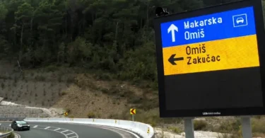 Plavi putokaz s natpisom Makarskog Omišu na horskoj cesti sa serpentinama