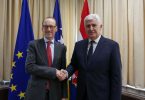 Dva čovjeka u odijelima rukovanju se pred zastavama EU i Austrije