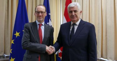 Dva čovjeka u odijelima rukovanju se pred zastavama EU i Austrije