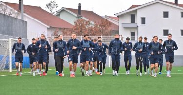 Fudbalski tim u plavim dresovima skupljen na terenu prije utakmice