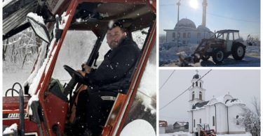 Muškarac u kabini crvenog traktora während zimskih radova sa crkvom u pozadini