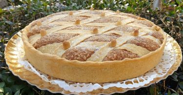 Zlatnasto-smeđa torta s ornamentalnom pletenom dekoracijom od tijesta na zlatnom tanjuru