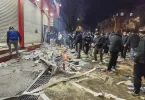 Policija i građani na ulici noću, razasuti predmeti i oštećenja uz zgradu