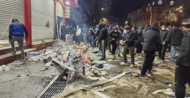 Policija i građani na ulici noću, razasuti predmeti i oštećenja uz zgradu