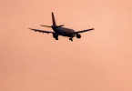 Silhueta putničkog aviona u letu protiv rozičastog neba tokom zalaska sunca