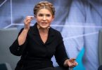 Žena u crnom odijelu govori na televizijskoj emisiji ili konferenciji