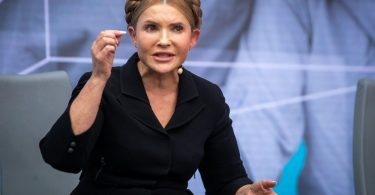 Žena u crnom odijelu govori na televizijskoj emisiji ili konferenciji