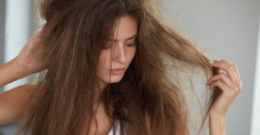 Žena s dugom, oštećenom i puštenkom kosom u rukama