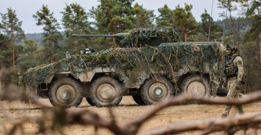 Teški vojni transporter s krovnom zaštitom parkiran u šumovitom terenu