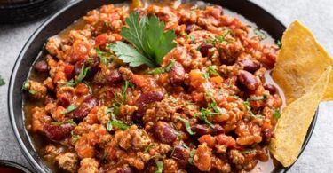Mljeveno meso pripremljeno u crnoj tepsiji s paradajzom, lukom i začinima, posluženo s pita kruhom