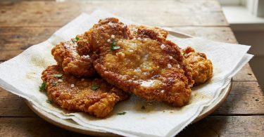 Nekoliko zlatno-smeđih pohanih šnicla na bijelom tanjuru