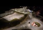 Noćni pogled na osvetljeno sportsko igralište s reflektorima i parkiralištem