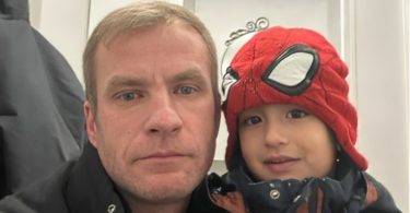 Muž i mali dječak u crvenom kapusu i majici Spider-Mana se grle i nasmijavaju