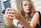 Mlada žena fotografira sebe pametnim telefonom na javnoj lokaciji