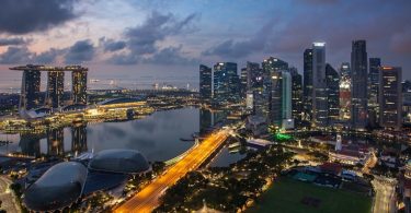 Panoramski pogled na Singapur tokom sumraka sa osvijetljenim nebodericama, lukom i mostovima