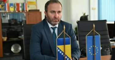 Muškarac u plavom odijelu za stolom sa zastavama ŽZH i EU