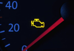 Upaljeni check engine signal na instrumentnoj ploči automobila s crvenom strelicom na brzinomjeru