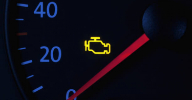 Upaljeni check engine signal na instrumentnoj ploči automobila s crvenom strelicom na brzinomjeru