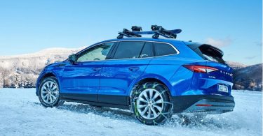 Plavi električni SUV vozilo parkirano na snijegu s krovnim prtljažnikom