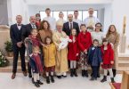 Velika obitelj s djetetom u crvenoj haljini tijekom krštenja