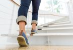 Osoba u plavim traperama penje se niz stepenice u interijeru