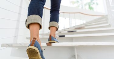 Osoba u plavim traperama penje se niz stepenice u interijeru