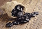 Suhe šljive izlijevaju se iz jutnog vrećice na drvenu površinu