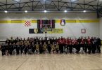 Učesnici ženskog košarkaškog turnira okupljeni na parketnom igralištu u sportskoj dvorani
