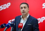 Muškarac u plavom odijelu govori na press konferenciji ispred SDP pozadine