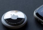 Srebrni Apple AirTag tracker s Apple logotipom na crnoj pozadini