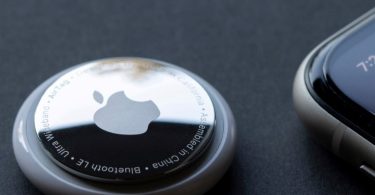 Srebrni Apple AirTag tracker s Apple logotipom na crnoj pozadini