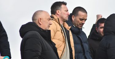 Muškarac u žutoj jakni i crnoj jakni na tribinama stadiona