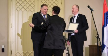 Tri muškarca u odijelu na ceremoniji dodjele odlikovanja, mikrofonom u prvi plan