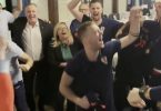 Grupa ljudi slave u zatvorenom prostoru, dizanjem ruku i smijehom