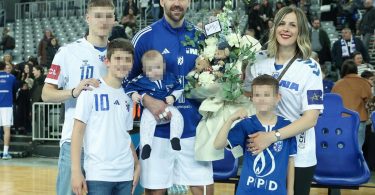Muškarac u plavoj majici sa obitelji na sportskom događaju