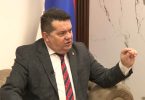 Muškarac u siva odijelu i crvenog kravatom gestikulira tijekom razgovora