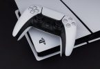Bijeli PlayStation 5 kontroler DualSense pored PS5 konzole na crnoj površini