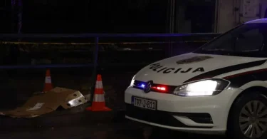 Policijski automobil s uključenim svjetlima noću pored mjesta događaja