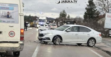 Bijeli automobil oštećen u sudaru na cesti, vozila i očevid na mjestu nesreće
